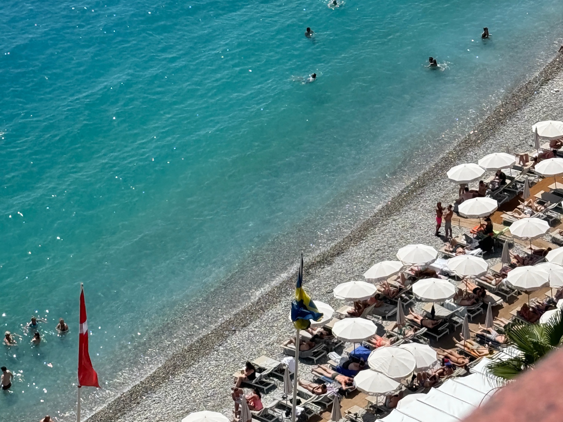 Aerial view of turquoise Mediterranean sea and white umbrellas on a Nice beach club, France