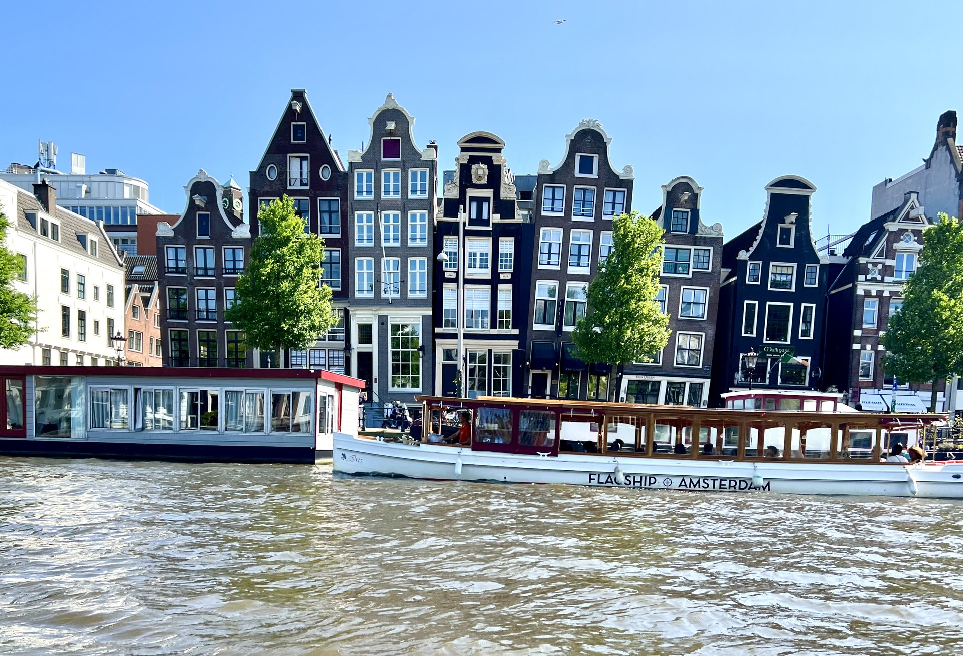 Historic Amsterdam canal houses with boats on a sunny day