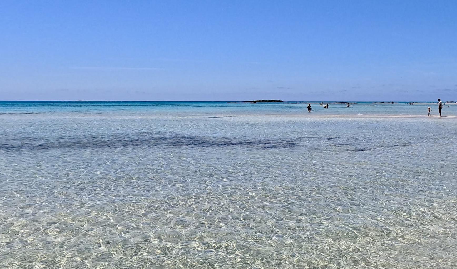 Crystal clear shallow water at Elafonissi Beach in Crete with people in the distance