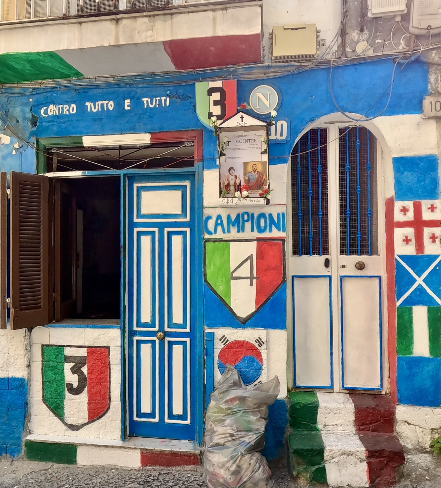 Colourful building in Naples painted with Napoli football club murals and Campioni shields