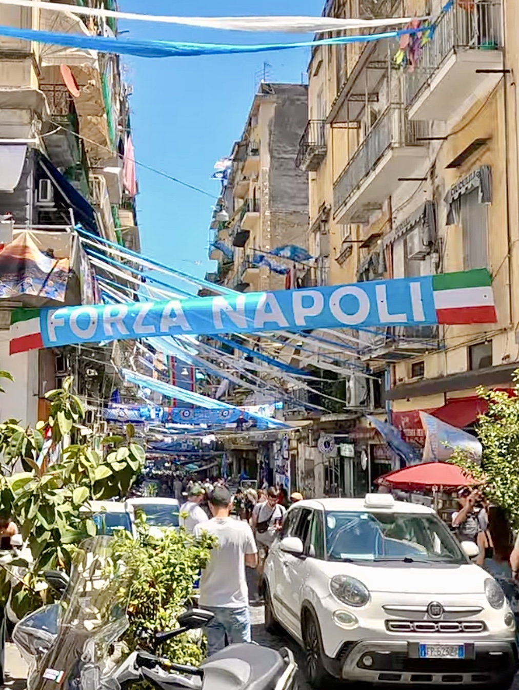 Forza Napoli banner stretched across a busy street during Serie A celebrations