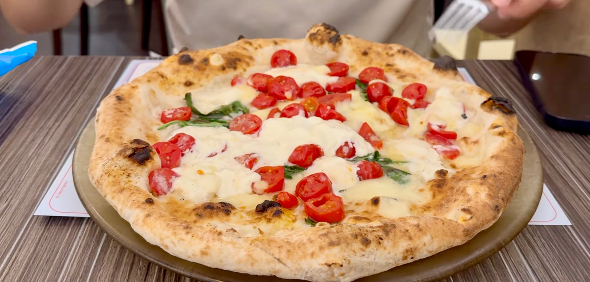 Wood-fired pizza topped with fresh tomatoes, mozzarella, and basil at Starita pizzeria in Naples